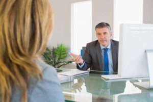 man behind desk talking to blond colleague