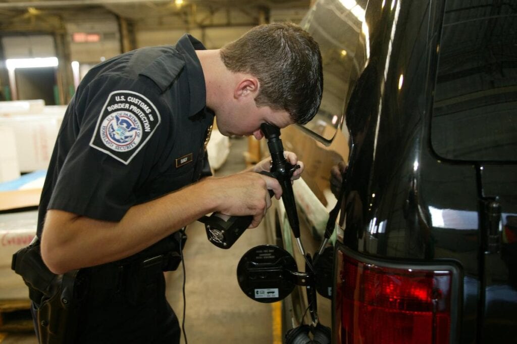 customs officer in san diego port examining gas tank for fentanyl
